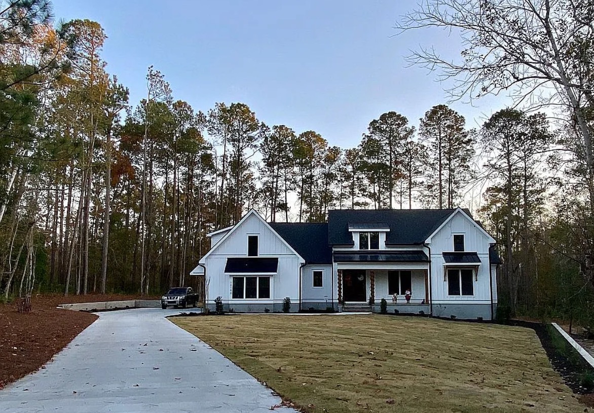 White home with a broad front lawn and tree-lined driveway